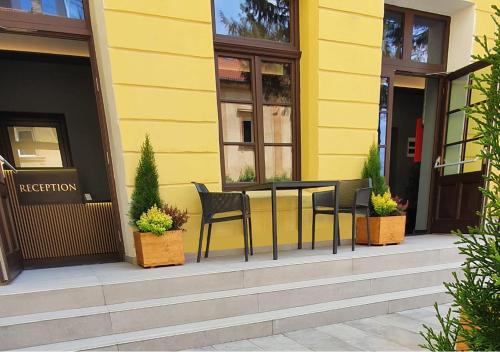 a table and chairs outside of a yellow building at JOYME Hotel in Sibiu