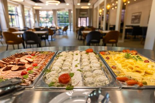 a buffet with several trays of food on a table at Hotel Kudowa Manufaktura Relaksu in Kudowa-Zdrój