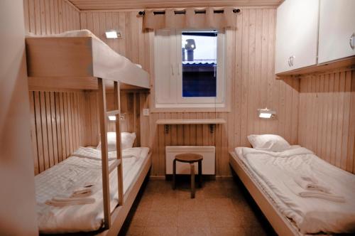 2 łóżka piętrowe w niewielkim pokoju z oknem w obiekcie Kåppas Cabin Village w mieście Björkliden