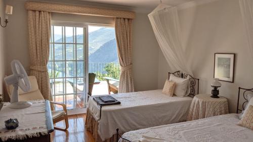a bedroom with two beds and a large window at Quinta da Galeira in Pinhão