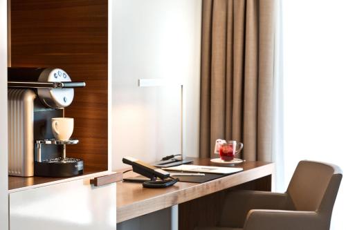 a hotel room with a desk with a lamp and a drink at Hotel 47° in Konstanz