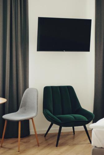 a green chair and a chair next to a wall at BOOGIE Home Kamienica Łódzka in Łódź