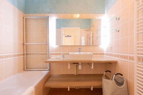 ein Badezimmer mit einem Waschbecken, einer Badewanne und einem Spiegel in der Unterkunft Quartier Vauban 2 bedroom apartment in Antibes