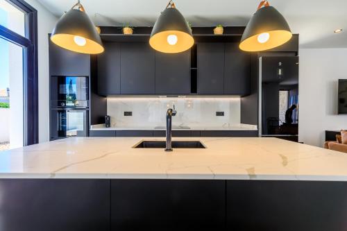a kitchen with black cabinets and a sink and lights at VILLA MI LUNA in Torrevieja
