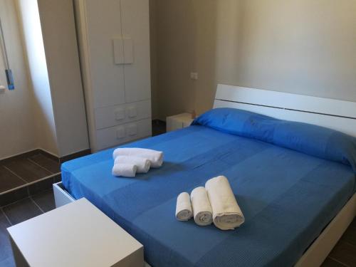 ein blaues Bett mit zwei rollenden Handtüchern darauf in der Unterkunft Scilla Upper Town in Scilla