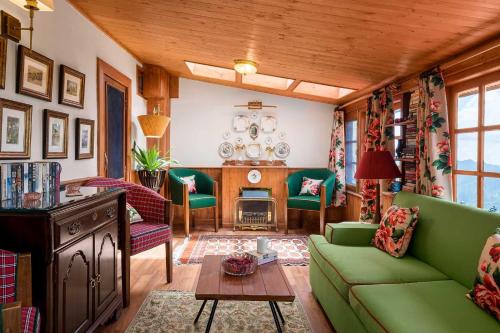 a living room with a green couch and chairs at StayVista at Sidhowal Lodge 1BR w Comp Breakfast in Shimla
