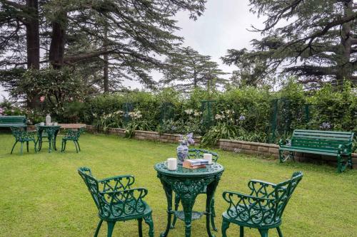 a table and chairs in a yard with a bench at StayVista at Sidhowal Lodge 1BR w Comp Breakfast in Shimla