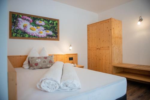 a bedroom with a white bed with a painting on the wall at Hotel Gran Pre in San Vigilio Di Marebbe