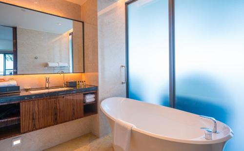 a bathroom with a tub and a sink and a mirror at Forest City Marina Hotel in Nusajaya