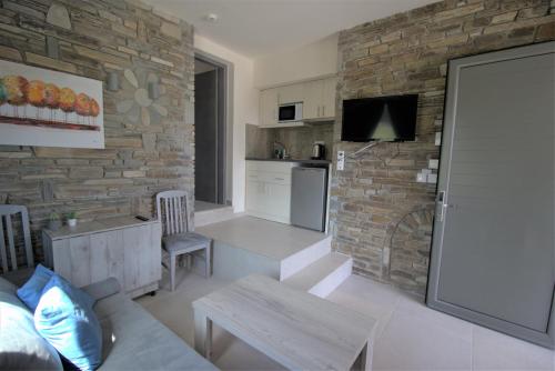a kitchen and living room with a stone wall at The Palms novasithonia in Vourvourou
