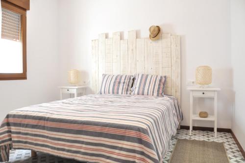 1 dormitorio con 1 cama con colcha a rayas en Ca Tía Teresa, en Denia