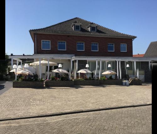 un grand bâtiment avec des parasols en face de celui-ci dans l'établissement Haus Wijnen, à Bad Bentheim