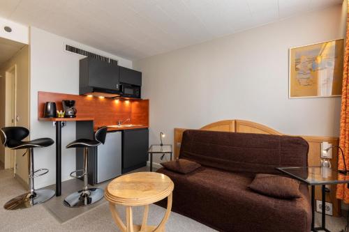 a living room with a couch and a table and a kitchen at The Originals Residence, Kosy Nancy Coeur de Ville in Nancy