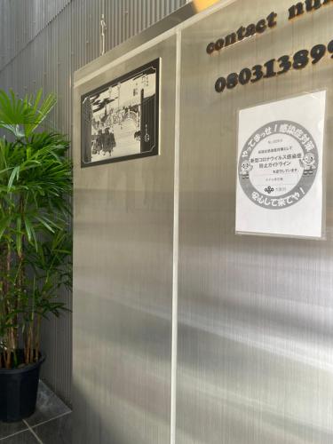 a metal wall with a picture and a sign on it at Hotel 草石庵 in Osaka