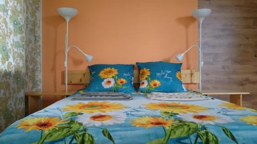 een bed met blauwe en gele bloemen erop bij Willow Apartments in Limbaži