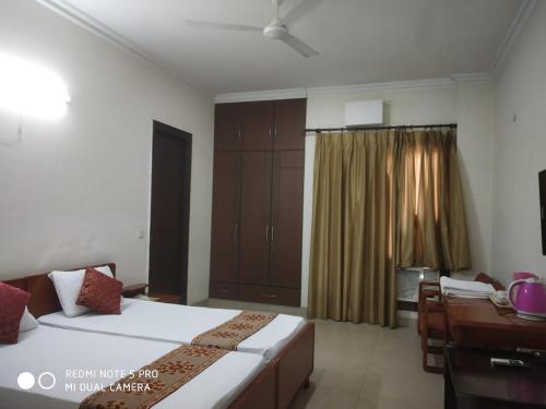 a hotel room with two beds and a desk and a desk at Deluxe Suite in Manor Inn Suites B-54, Sector-92 in Noida