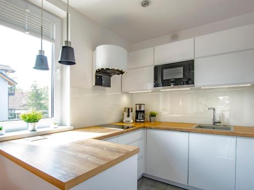 una cucina con armadi bianchi e ripiano in legno di VacationClub - Pionierów 6 Apartament 15 a Mielno