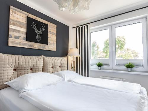 a bedroom with a white bed and two windows at VacationClub - Pionierów 6 Apartament 15 in Mielno