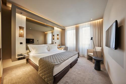 um quarto de hotel com uma cama grande e uma televisão em PortoBay Teatro em Porto