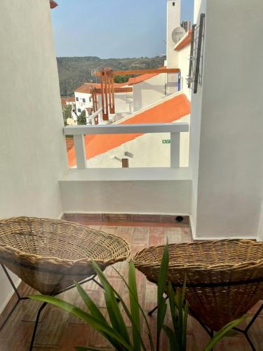 a balcony with two chairs and a view of a building at Casas Do Moinho - Turismo De Aldeia in Odeceixe