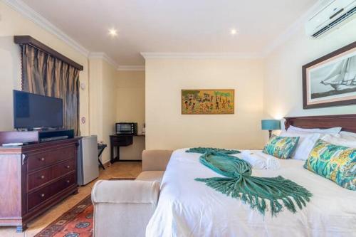 a bedroom with a large bed and a television at La Posada Umhlanga in Durban
