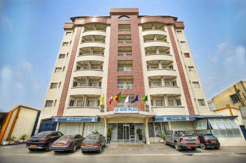 un edificio alto con coches estacionados frente a él en Bano Palace Hotel, en Douala