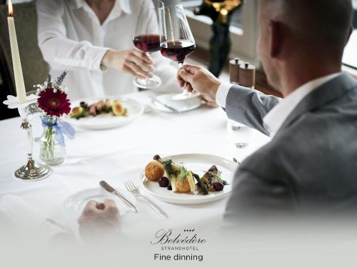 Ein Mann, der mit einem Glas Wein am Tisch sitzt. in der Unterkunft Belvédère Strandhotel in Spiez