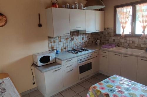 une petite cuisine avec des armoires blanches et un micro-ondes dans l'établissement Maison calme indépendante et vue sur les montagnes, à Briançon