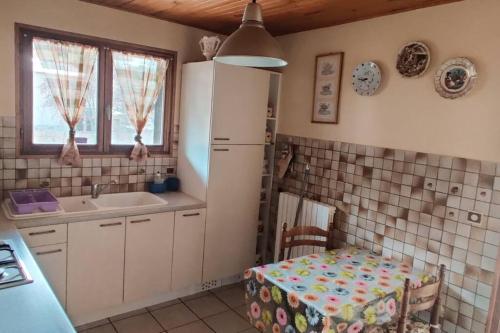 La cuisine est équipée d'une table, d'un évier et d'un réfrigérateur. dans l'établissement Maison calme indépendante et vue sur les montagnes, à Briançon