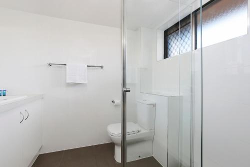 a white toilet sitting next to a shower in a bathroom at Wunpalm Motel & Holiday Cabins in Maroochydore