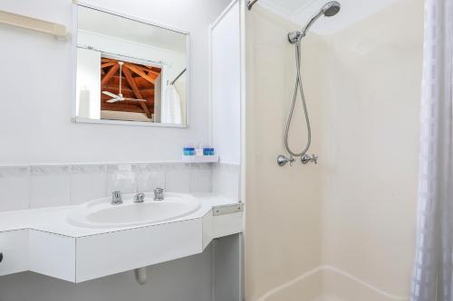 a white bathroom with a sink and a shower at Wunpalm Motel & Cabins - Late check-in available in Maroochydore