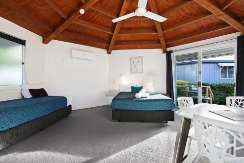 a bedroom with two beds and a ceiling fan at Wunpalm Motel & Cabins - Late check-in available in Maroochydore