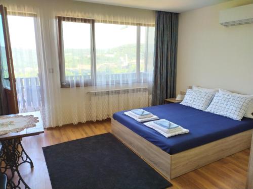a bedroom with a bed with blue sheets and windows at Stefi house in Veliko Tŭrnovo