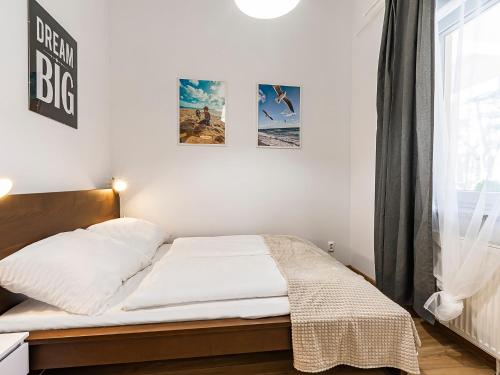 VacationClub - Olymp Apartment 502A في كولوبرزيغ: غرفة نوم بسرير وملاءات بيضاء وملصقات على الحائط