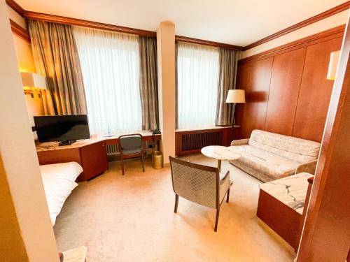 a hotel room with a couch and a bed and a desk at Gästehaus Sophienstraße in Stuttgart