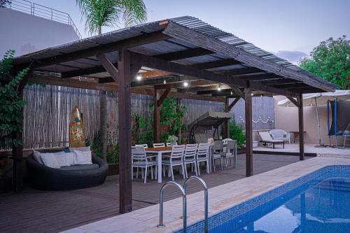 a wooden pergola with a table and chairs next to a pool at Apartment Caesarea 38 in Caesarea