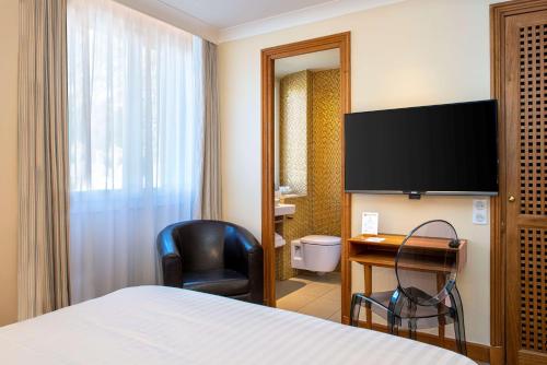 a hotel room with a bed and a desk and a television at Best Western Premier Montfleuri in Sainte-Maxime