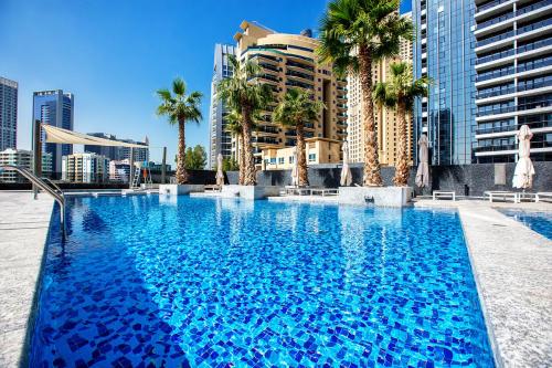 a large swimming pool with palm trees and buildings at Sparkle Tower, Dubai Marina in Dubai