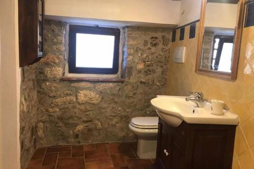 baño con lavabo y aseo y ventana en La casa all'Arco, en Campiglia dʼOrcia