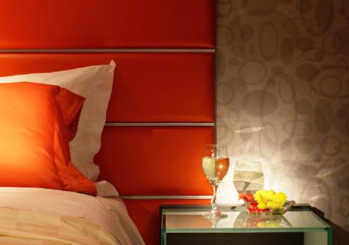 فندق كوزمو هونغ كونغ في هونغ كونغ: سرير مع اللوح الأمامي الأحمر وكأسين من النبيذ