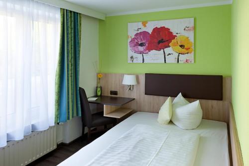 um quarto de hotel com uma cama, uma secretária e uma janela em Hotel Blauer Karpfen em Oberschleißheim