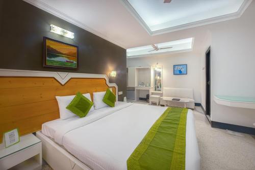 a bedroom with a large white bed with green accents at Treebo Green View, Park Circus in Kolkata