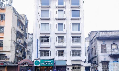 un grand bâtiment blanc avec un panneau de rue devant lui dans l'établissement Treebo Trend Green View, à Kolkata
