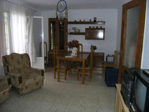 sala de estar con mesa, sillas y TV en Piso en Sevilla Este en Sevilla