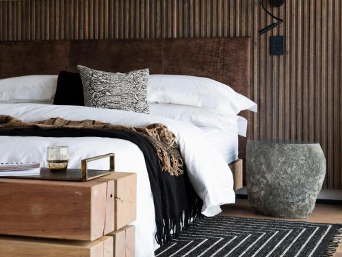 Schlafzimmer mit einem weißen Bett mit einem Kopfteil aus Holz in der Unterkunft Askara Haus in Pretoria