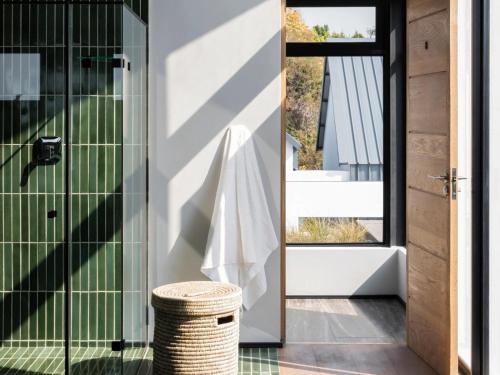 uma casa de banho com uma cabina de duche em vidro e um banco de vime em Askara Haus em Pretoria