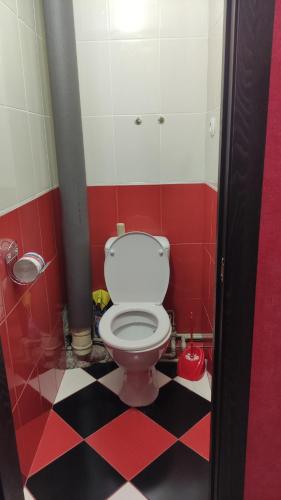La salle de bains est pourvue de toilettes au sol en damier rouge et noir. dans l'établissement Затишна квартира, à Tcherkassy
