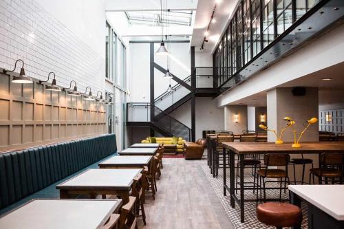 a restaurant with tables and chairs and a staircase at Chapter Kings Cross in London in London
