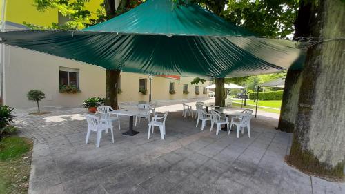 a patio with white tables and chairs under a green umbrella at Park Hotel Fantoni in Tabiano