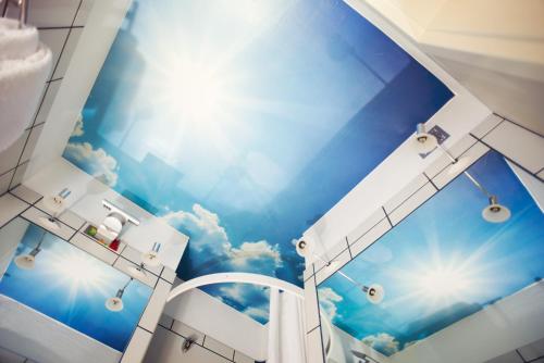 a bathroom with a mural of a blue sky at NunoHotel in Cologne